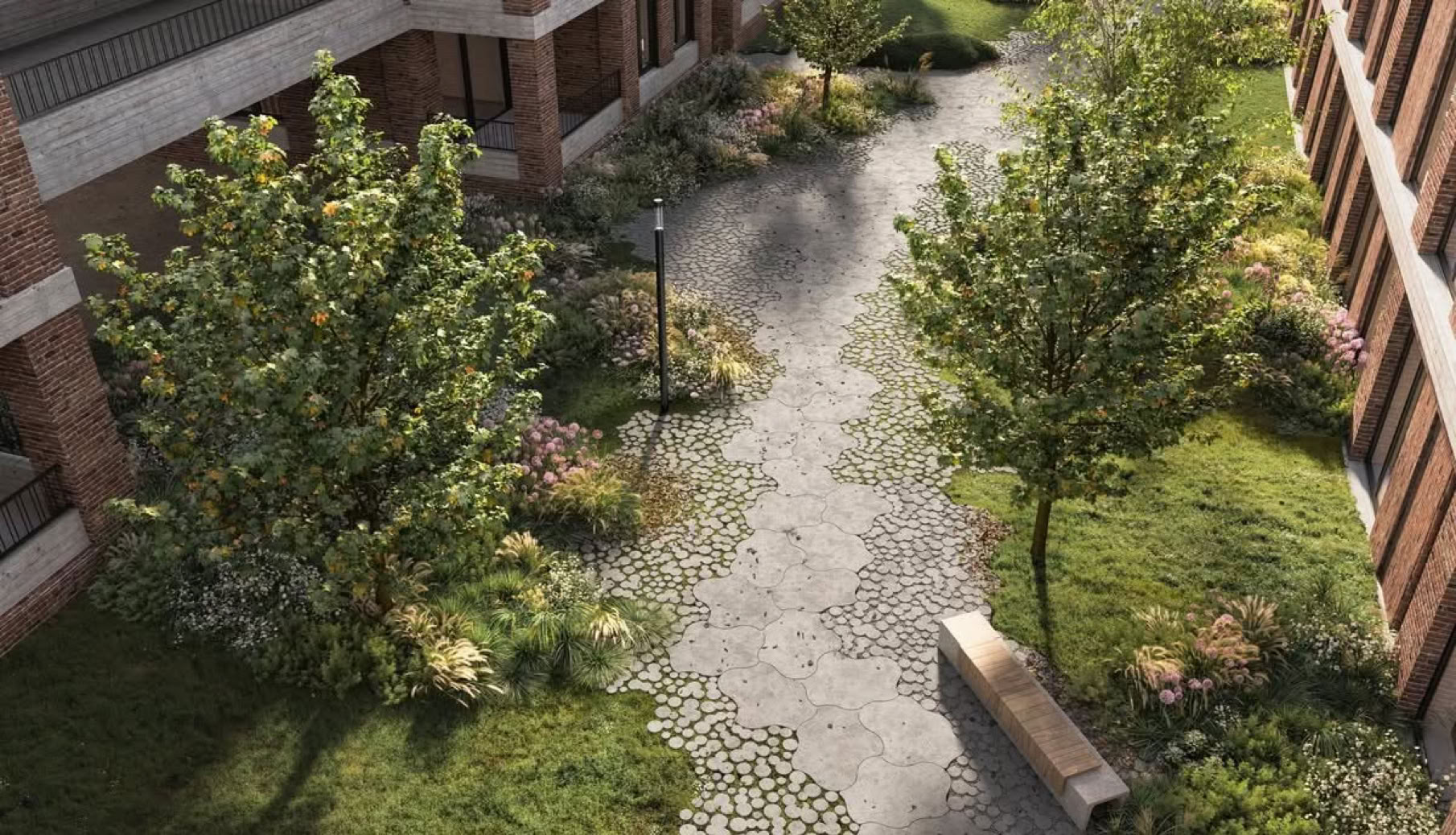 Dalles Lily Engazonable Vue aérienne d'une cour avec des arbres, un chemin pavé, un banc et des bâtiments en briques autour.